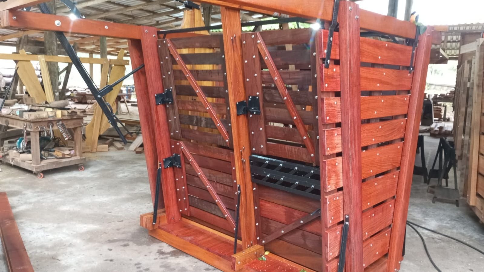 Detalhe de madeira vermelha envernizada com parafusos e ferragem preta